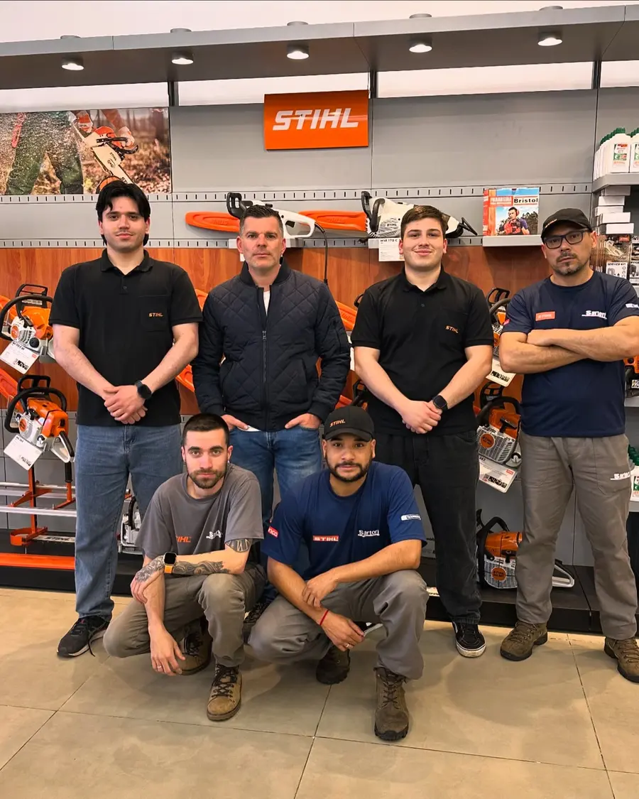 Equipe da Sartori Máquinas em frente à parede de motosserras STIHL